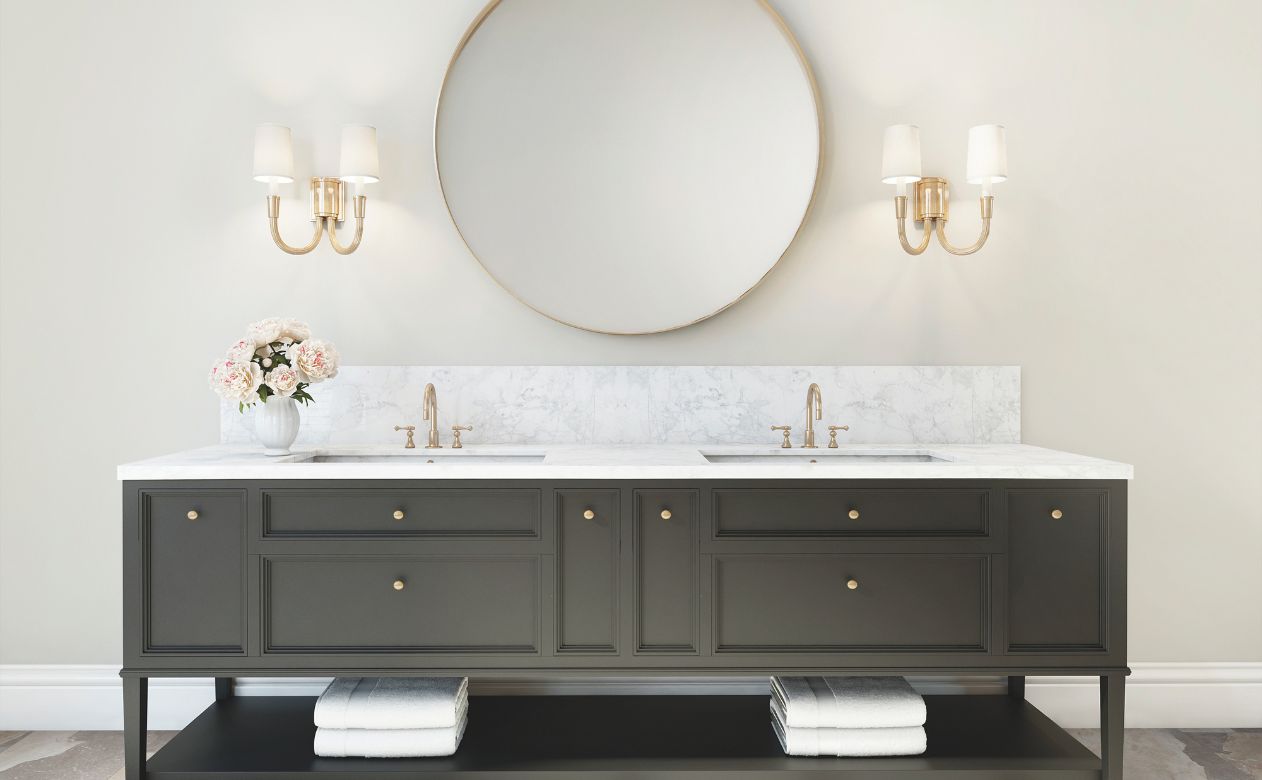 bathroom vanity design with round mirror, gold hardware, and black cabinets